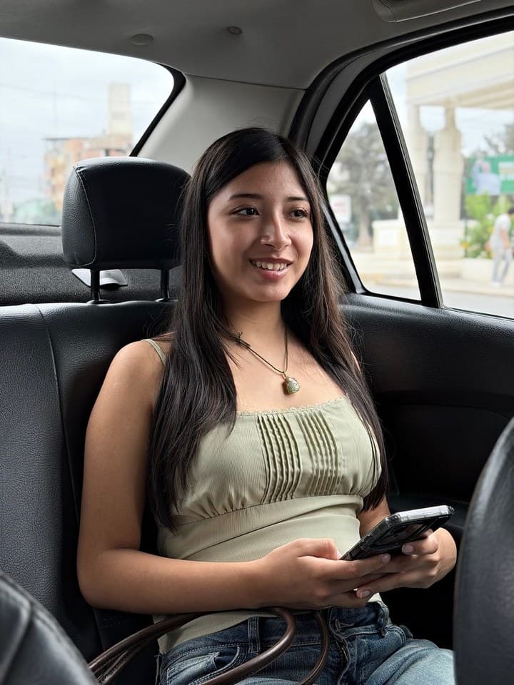 Pasajera sonriente en un taxi de Pinos Chiclayo con la app en la mano